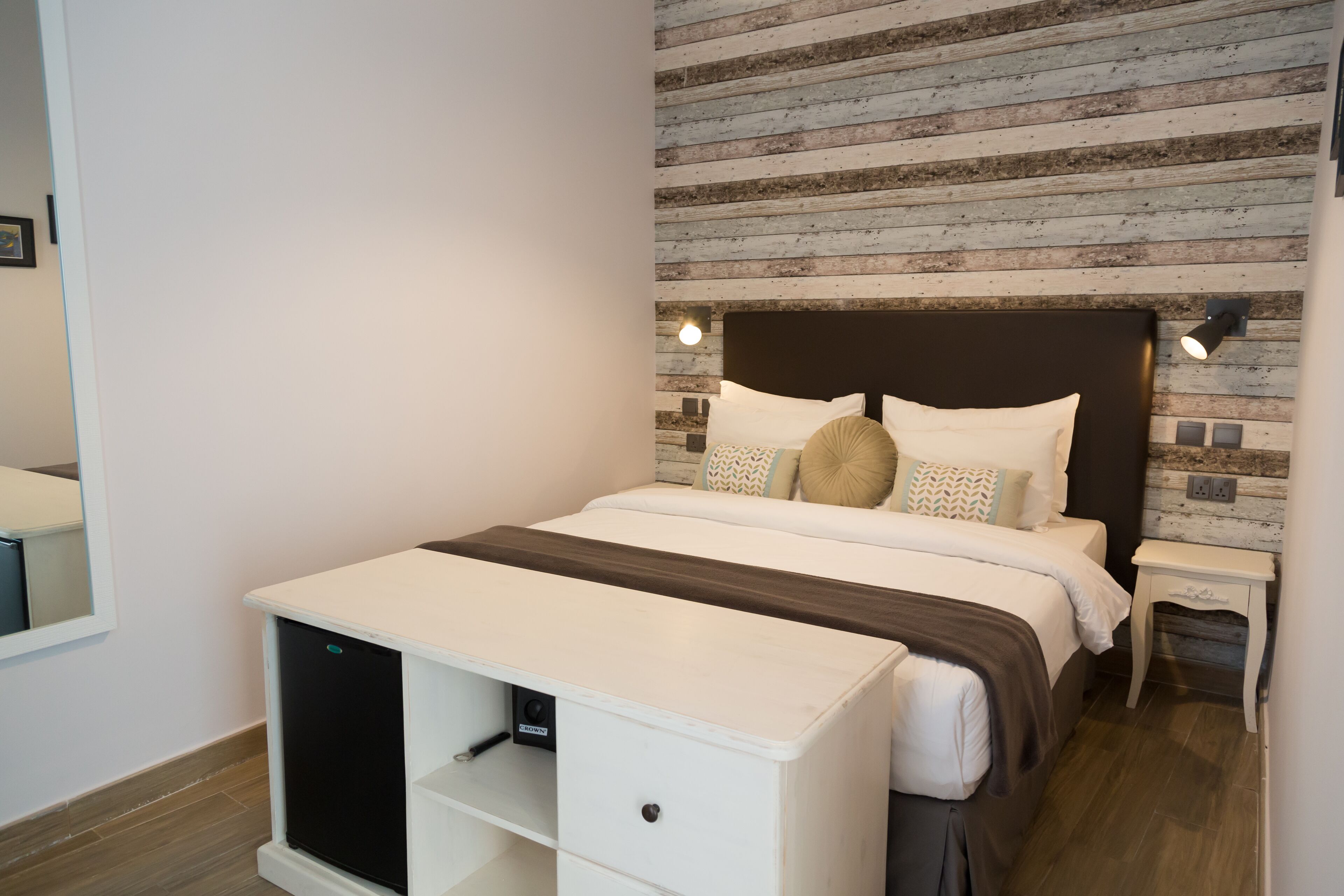 Un dormitorio con cama, mesitas de noche y un escritorio integrado.