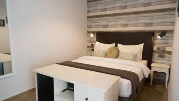 Un dormitorio con cama, mesitas de noche y un escritorio integrado.