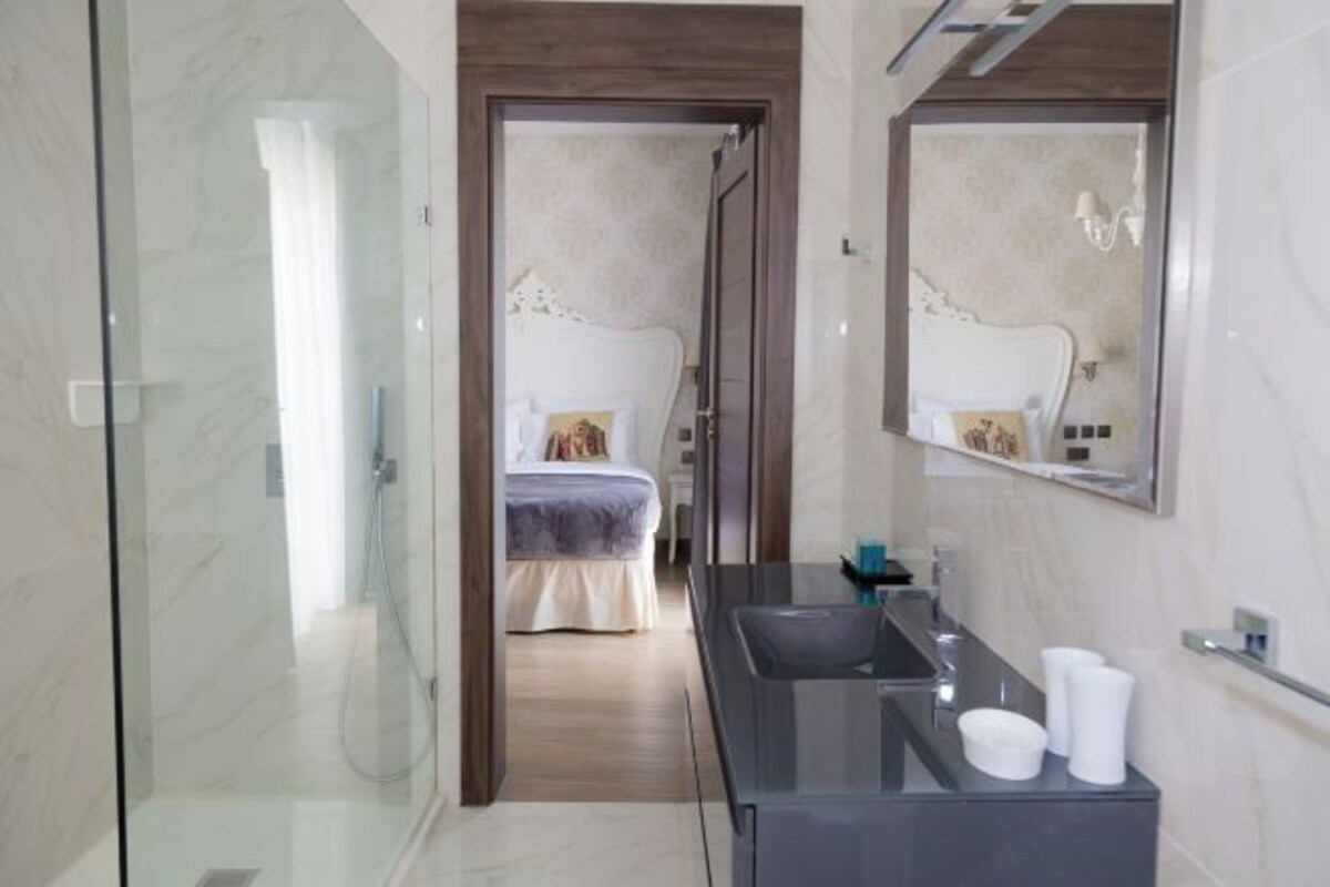 A modern bathroom with a glass shower enclosure, a dark vanity, and a large mirror.