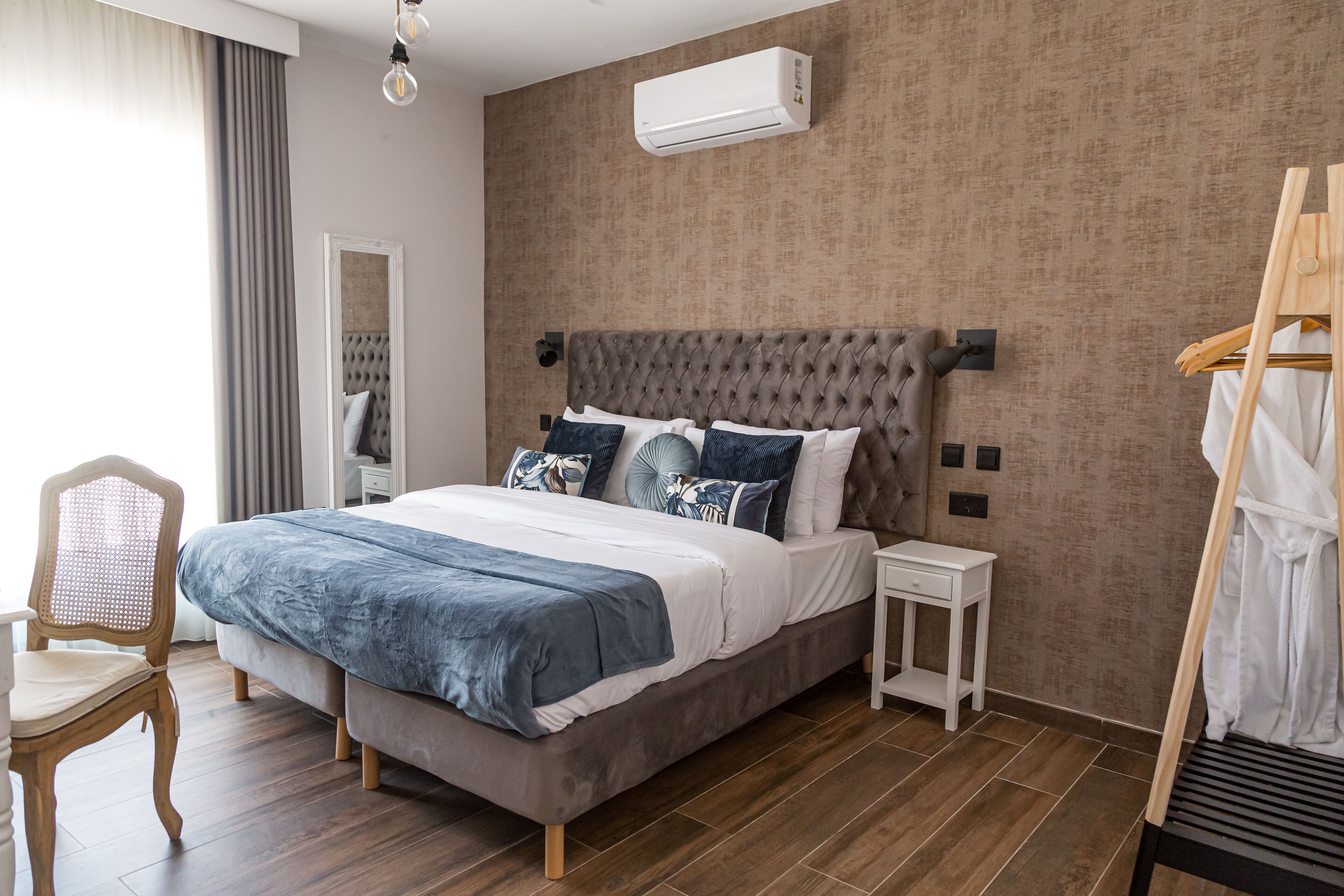 Un dormitorio moderno con una cama grande, una mesita de noche, una silla y un armario.