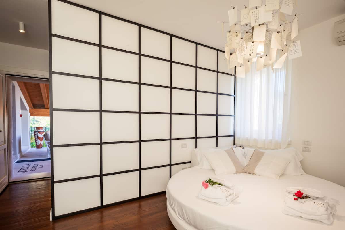 Ein Hotelzimmer mit einem großen Bett, einer verschiebbaren Shoji-Schirmwand und Blick ins Freie.
