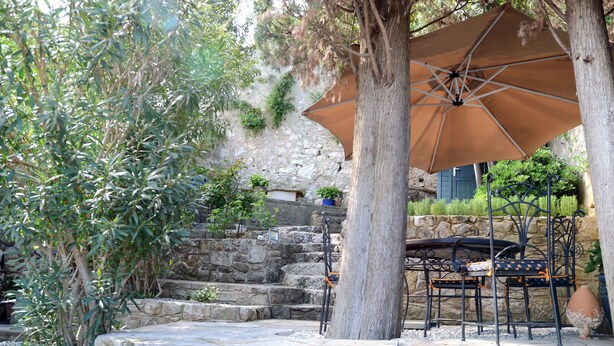 A stone staircase leading up to a stone wall, surrounded by greenery and a large tree. - Villa Orh (Rovinj)