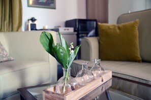 A living room with a glass coffee table holding a vase with green leaves and white flowers. - Villa Orh (Rovinj)
