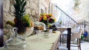 A table with a variety of food items and a vase of flowers, set against a stone wall with a railing in the background. - Villa Orh (Rovinj)
