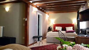 A bedroom with a red headboard, a bed with white and red bedding, a bedside table with a lamp, and a television on a wooden stand. - Villa Orh (Rovinj)