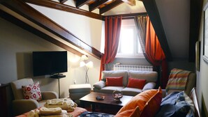 A cozy loft-style room with a sofa, a coffee table, and a TV mounted on the wall. - Villa Orh (Rovinj)