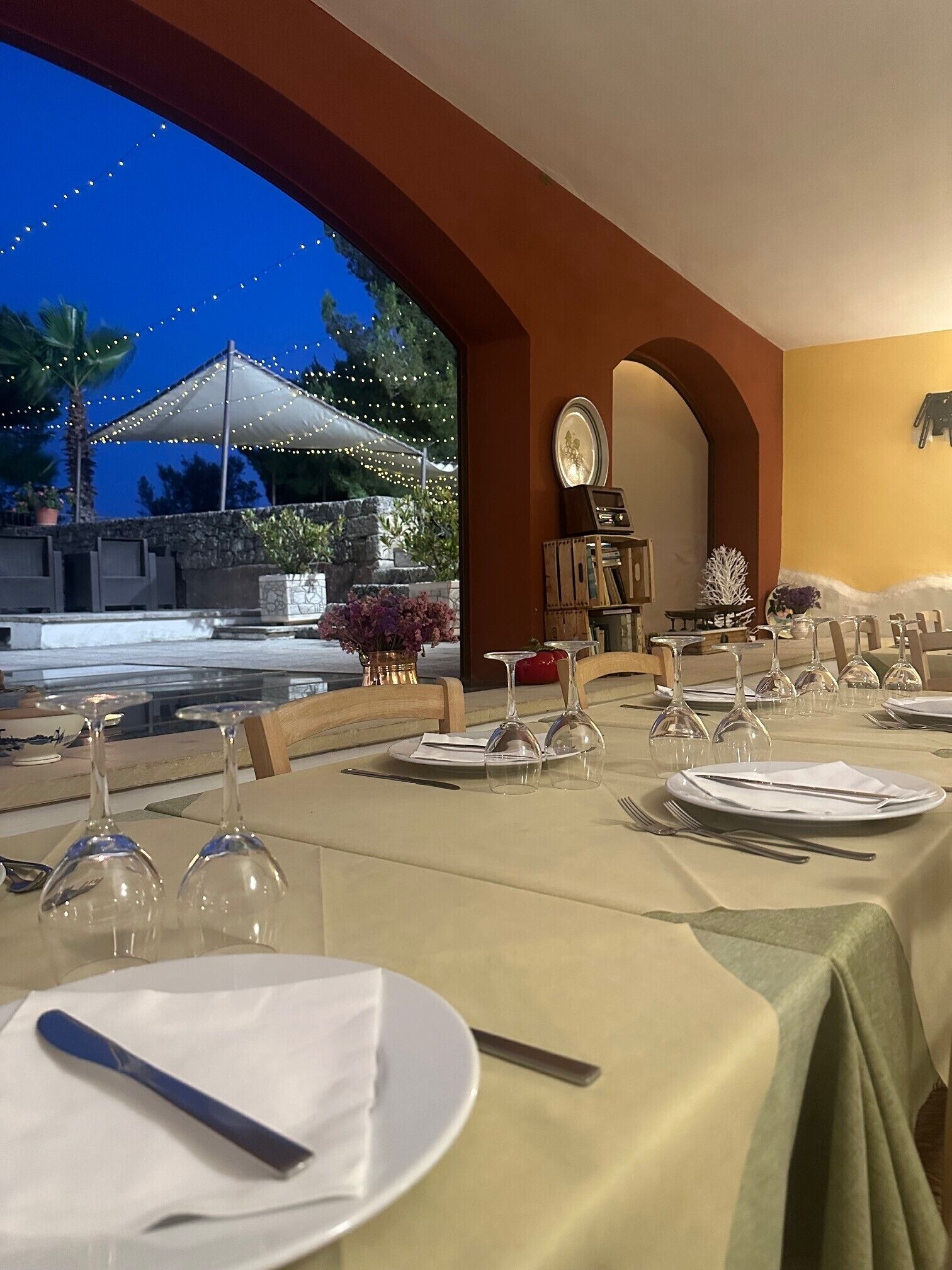 A dining area with tables set for a meal, a view of the outdoors, and a decorative archway.
