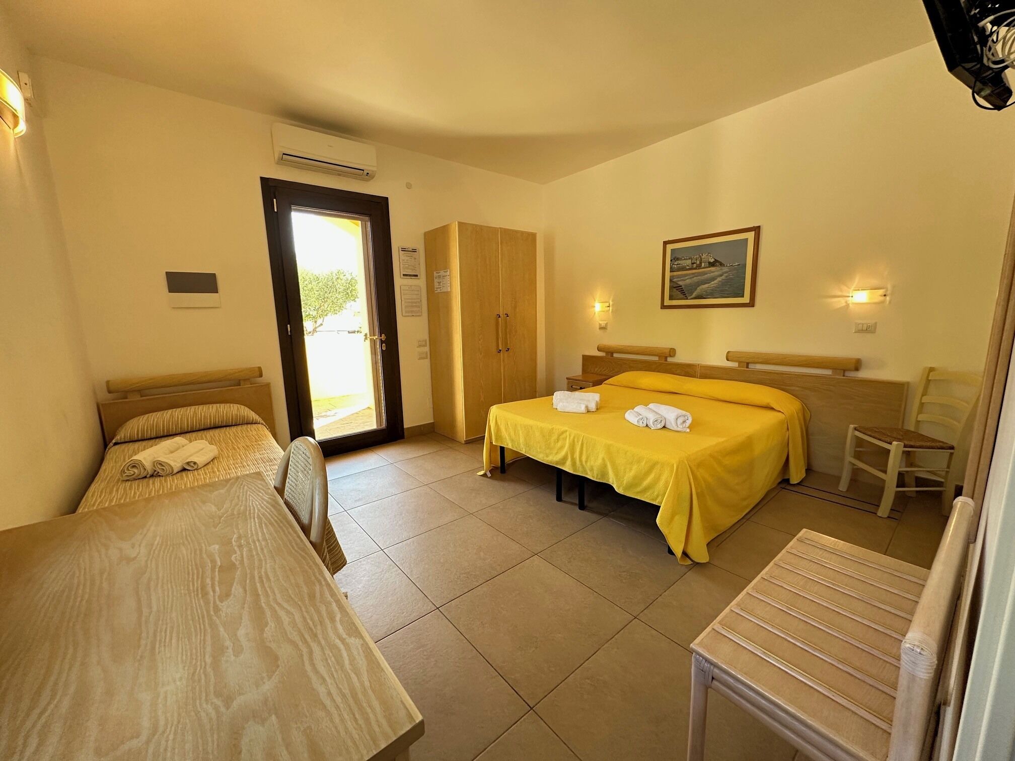 A hotel room with two beds, a desk, a chair, and a wardrobe.