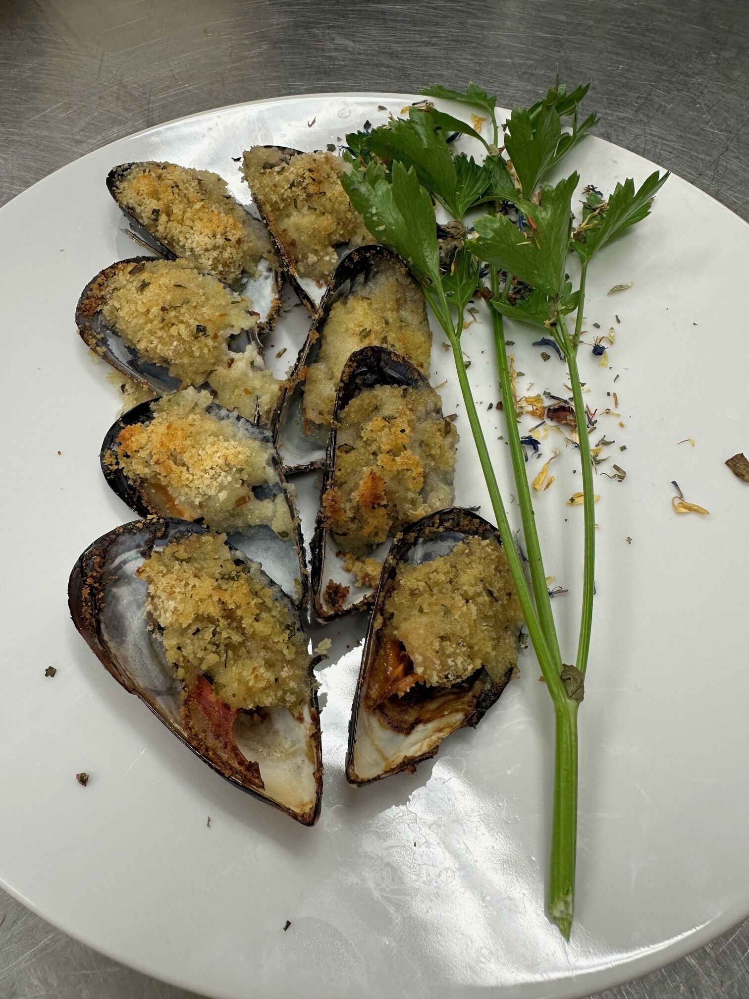 A plate of mussels with breadcrumbs and parsley.