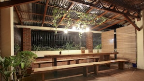 Un patio exterior con bancos de madera y plantas en macetas.