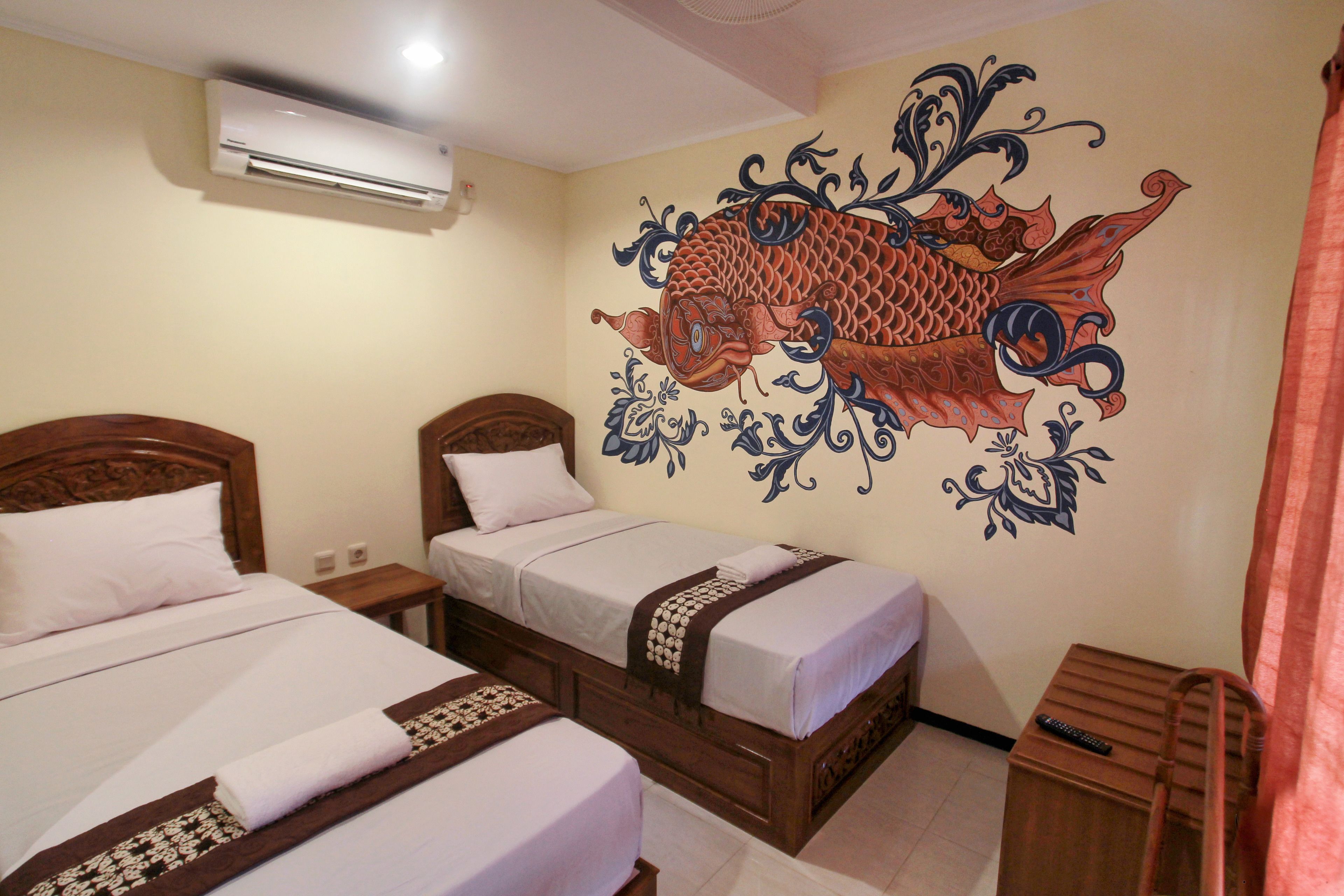 A hotel room with two wooden beds, a wall mural of a fish, and a wooden nightstand with a remote control.