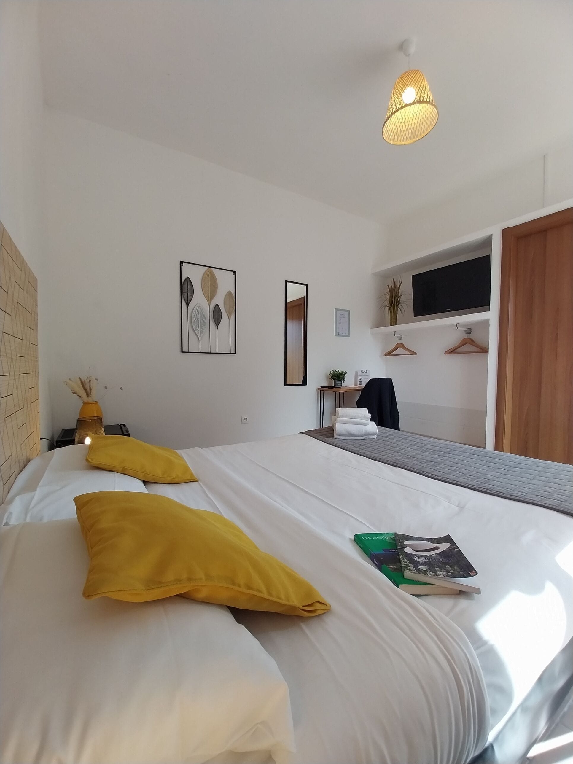 Habitación de hotel con dos camas, un espejo grande, un televisor de pantalla plana y un armario de madera.