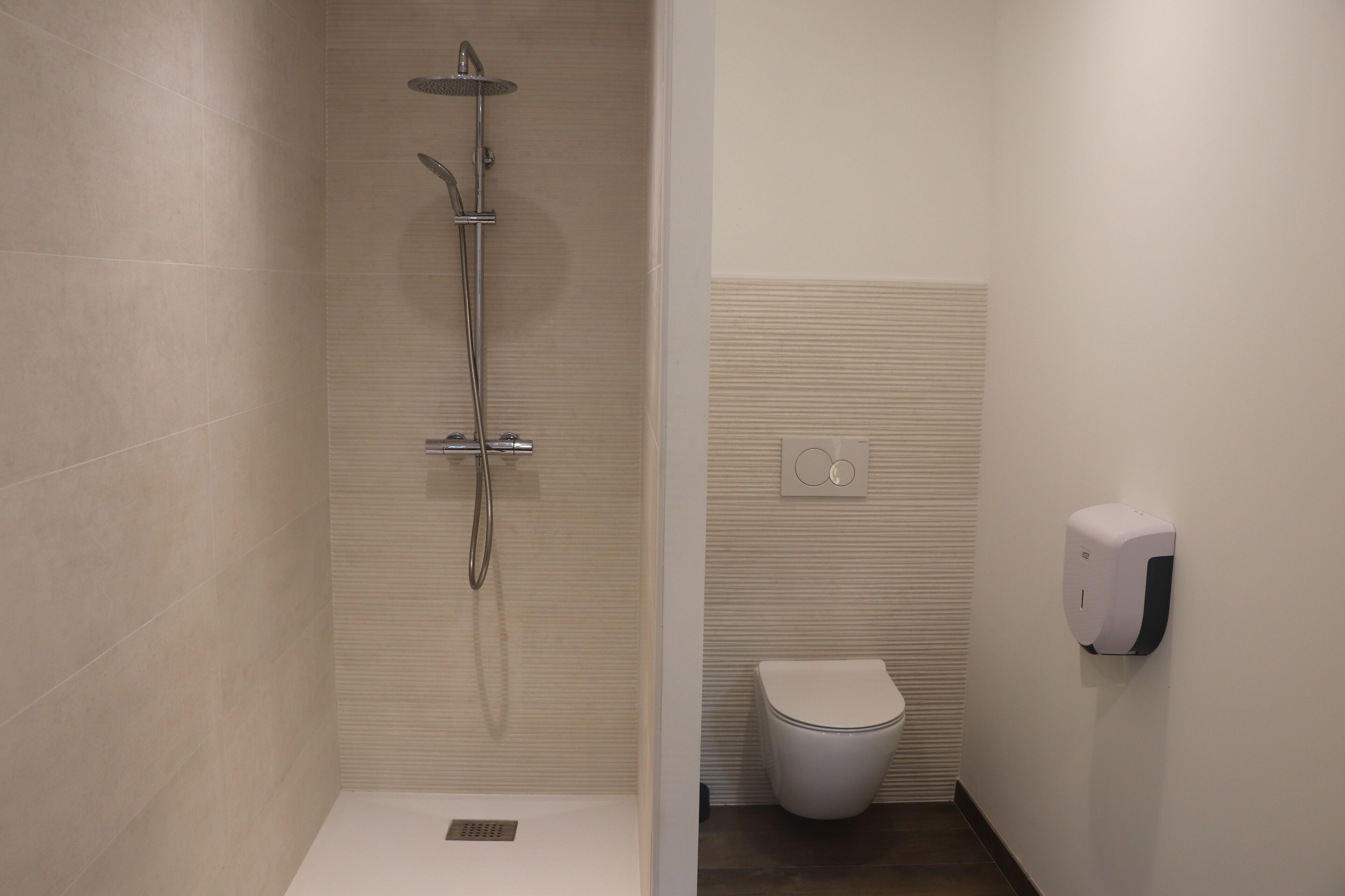 Un bagno con doccia, toilette e asciugatore automatico.