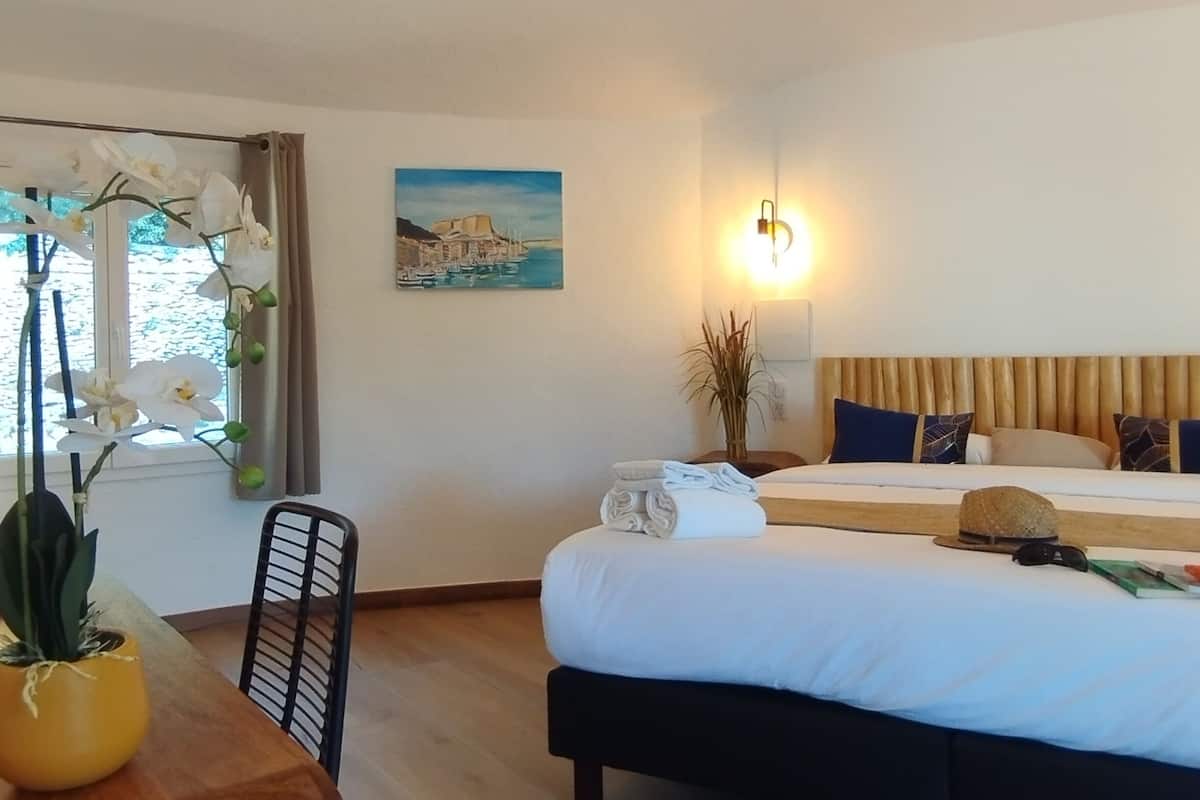 A hotel room with a bed, a dining table, and a window with curtains.