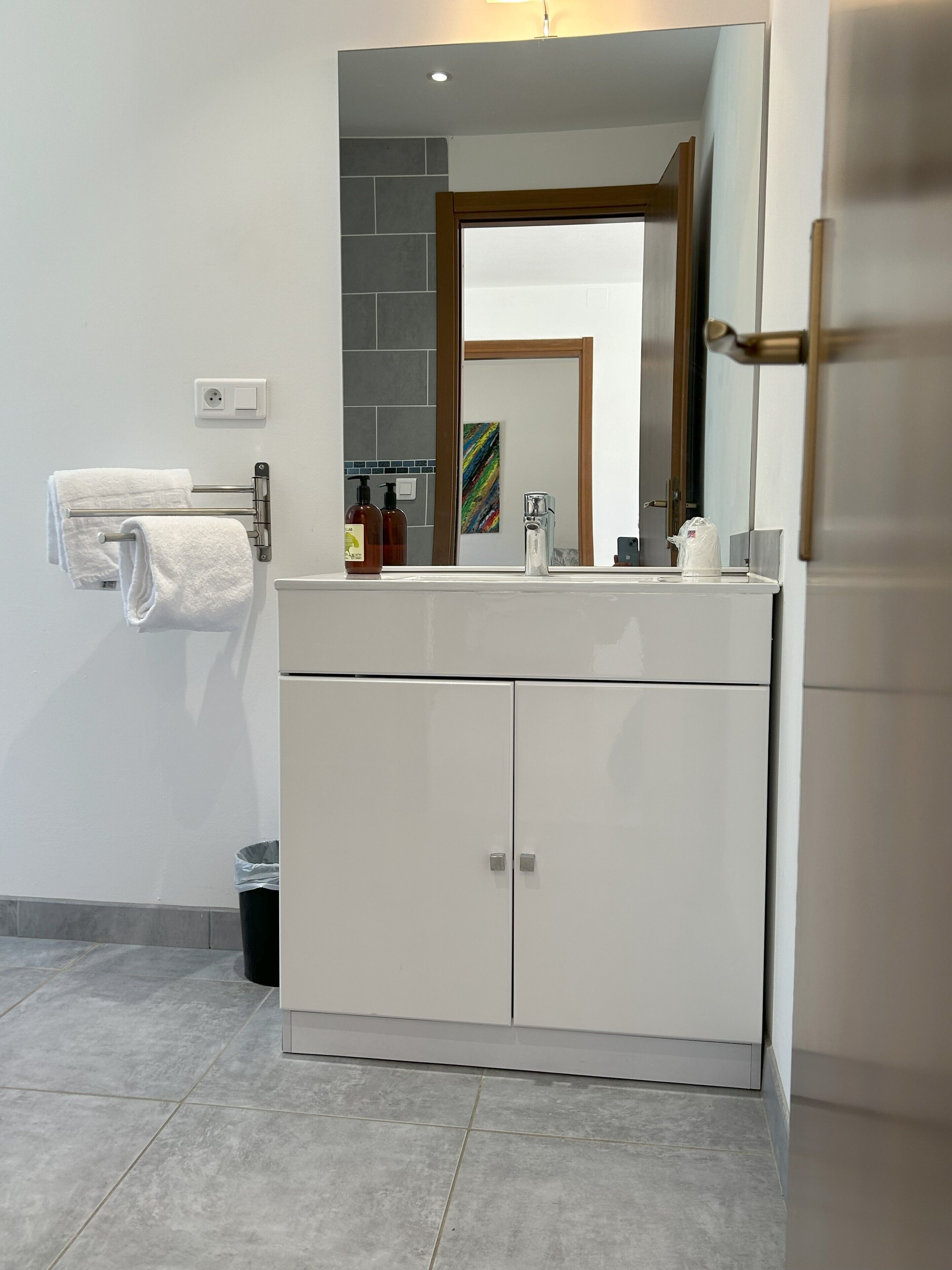Un baño moderno con tocador blanco, espejo y barra para toallas.