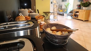 A kitchen area with a toaster, a basket of bread, and a coffee maker. - Hôtel Padolo (Bonifacio)