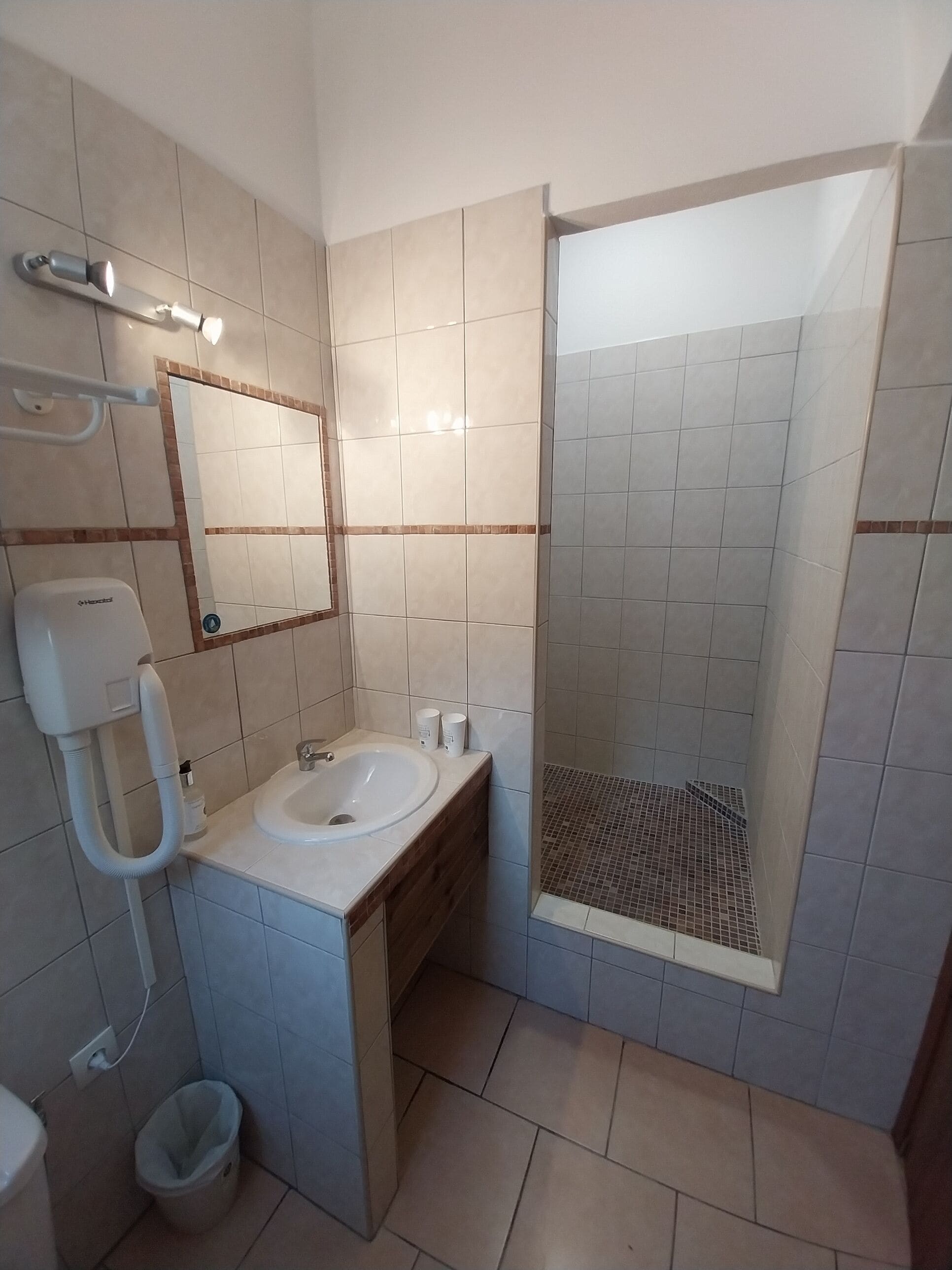 A modern bathroom with a sink, mirror, and shower.