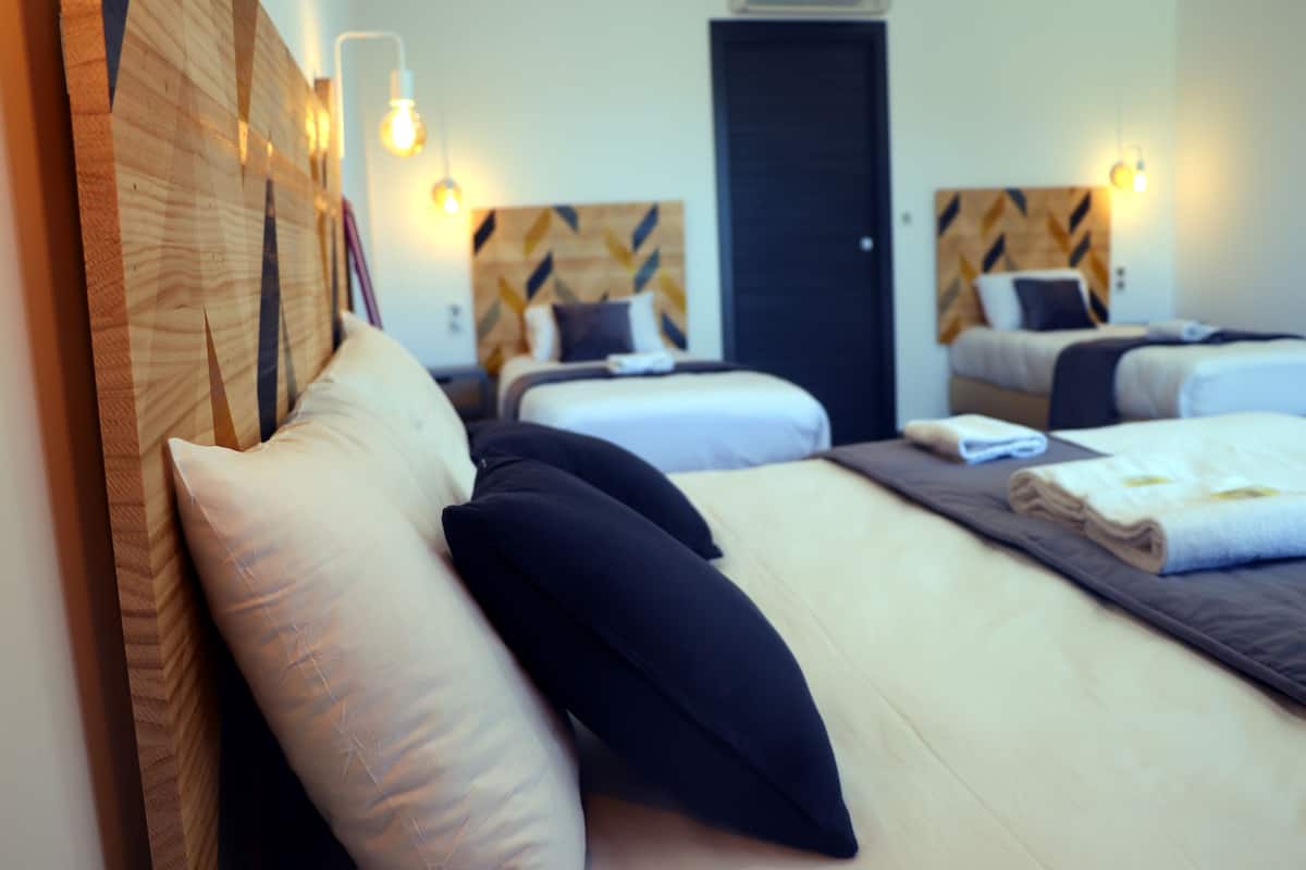 A hotel room with two beds, each with a headboard, pillows, and a folded towel.