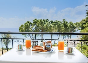 A table with breakfast items and drinks on a balcony overlooking a scenic view. - Theodora Apartments (West Mani)