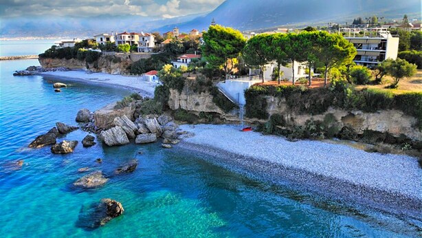 A coastal town with a clear blue sea, rocky shoreline, and buildings with balconies overlooking the water. - Theodora Apartments (West Mani)