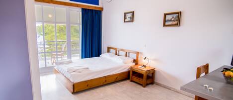 Un dormitorio con cama, mesita de noche, lámpara y una zona de comedor con mesa y sillas.