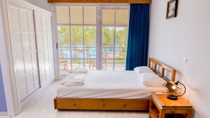 A bedroom with a bed, bedside table, and a view of the outside. - Theodora Apartments (West Mani)