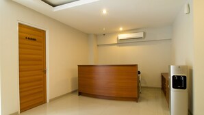 A reception area with a wooden reception desk, a water dispenser, and a closed door labeled "R-MANAGER". - RedDoorz Plus @ Setiabudi Tengah (Jakarta)