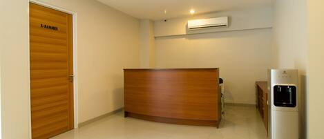 A reception area with a wooden reception desk, a water dispenser, and a closed door labeled "R-MANAGER".