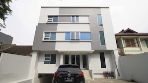 A modern two-story residential building with a car parked in the driveway. - RedDoorz Plus @ Setiabudi Tengah (Jakarta)