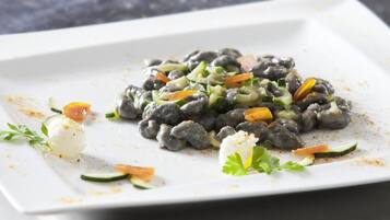 Un plato blanco con porción de frijoles negros, verduras y una cucharada de crema.