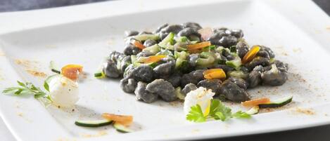 A white plate with a dish of black beans, vegetables, and a dollop of cream.