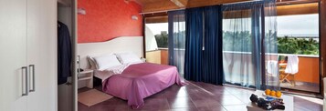 Un dormitorio con cama, mesita de noche, ventana con cortinas y vista al exterior.