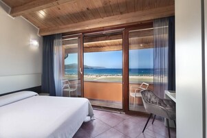 Habitación de hotel con cama, escritorio y vista al mar.