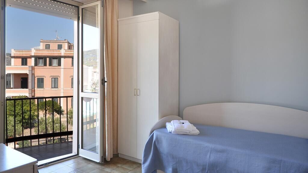 Quarto de hotel com cama, guarda-roupa e varanda com vista para edifícios.