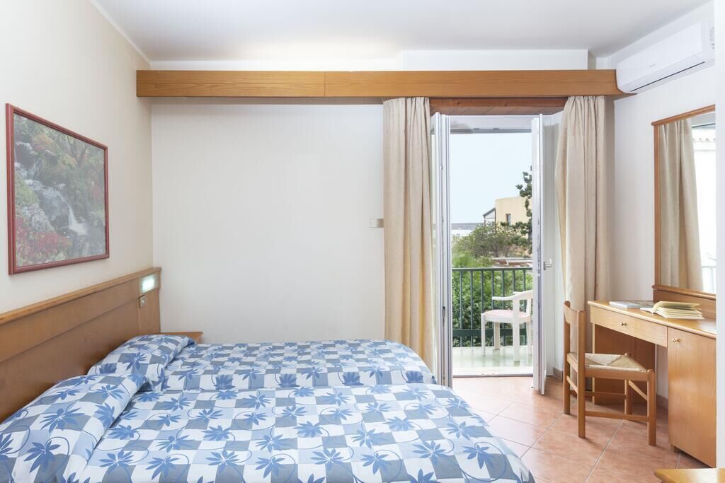 Een hotelkamer met een bed, een bureau en een balkon met uitzicht.