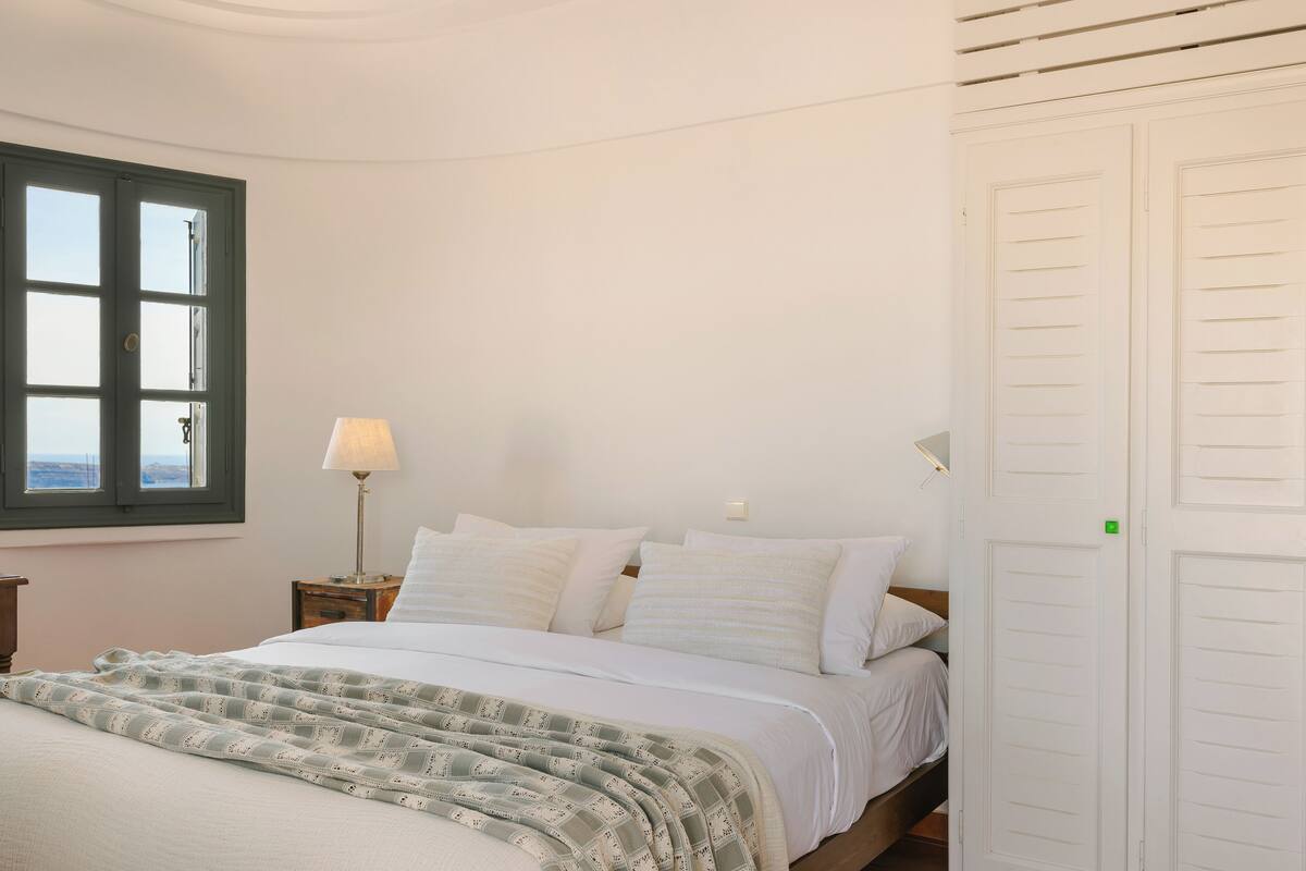 A bedroom with a bed, a window, a nightstand, and a wardrobe.