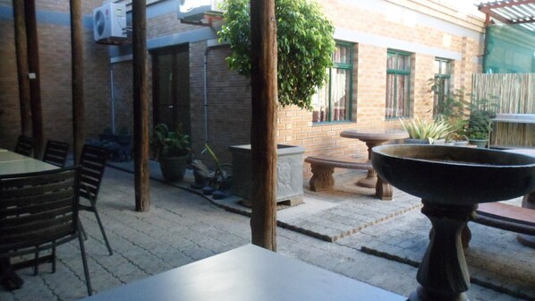An outdoor patio area with brick walls, a table, chairs, and potted plants. - Airport Hotel Maun (Maun)