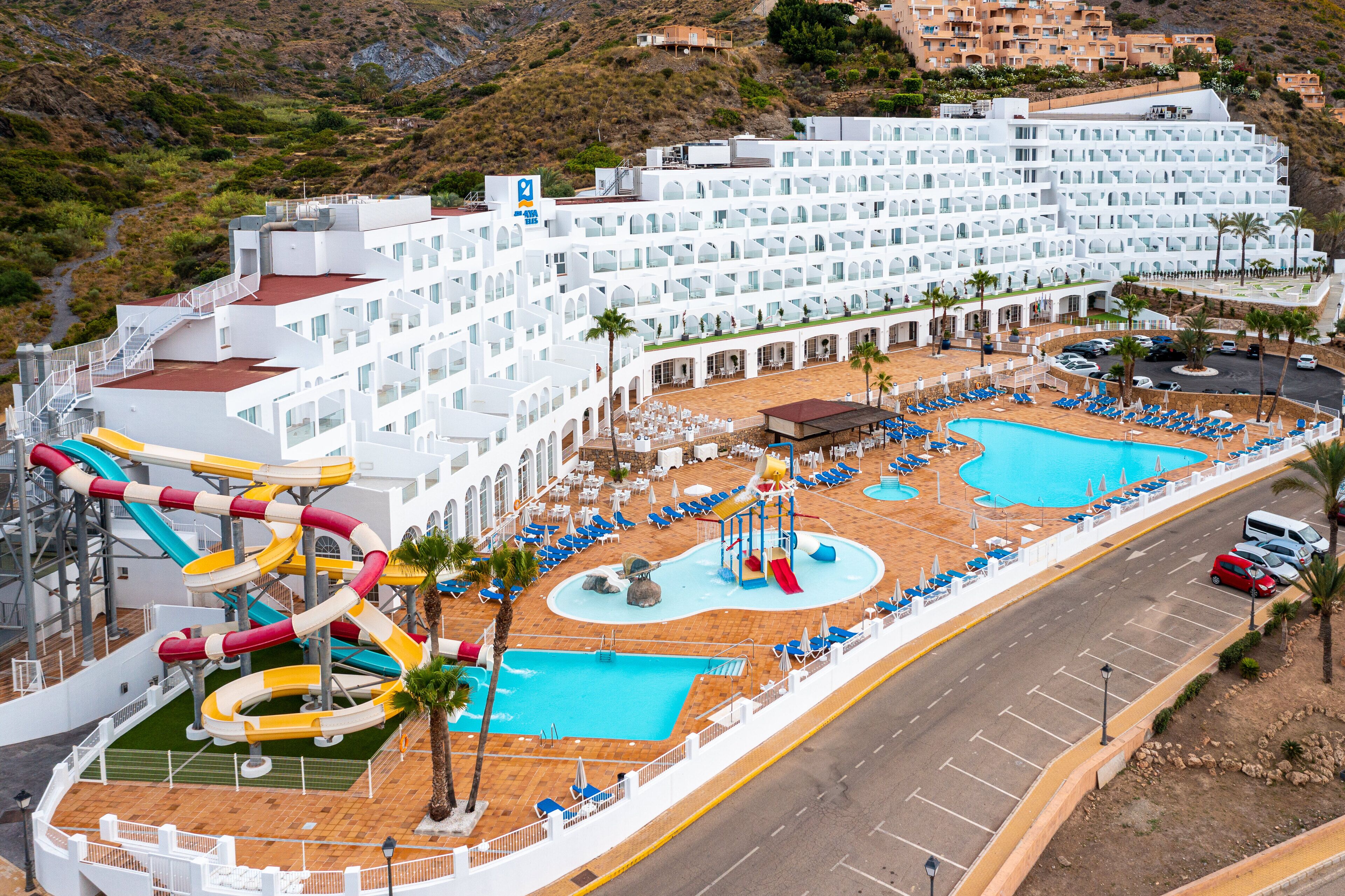 Un gran resort con varias piscinas, parque acuático y un edificio de hotel con balcones.