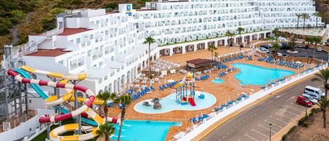 Un gran resort con varias piscinas, parque acuático y un edificio de hotel con balcones.