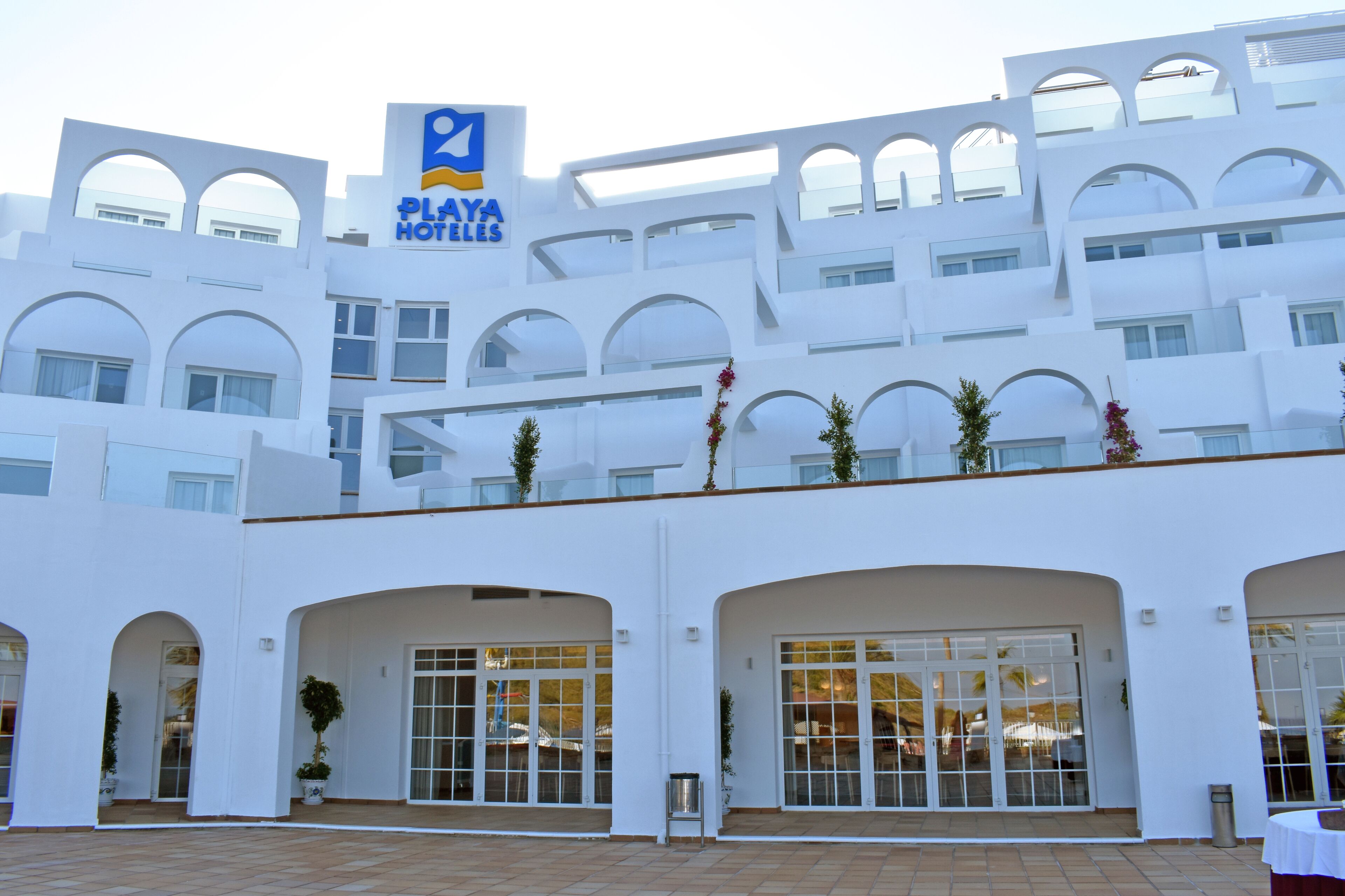 A modern hotel with a white facade, multiple balconies, and large windows.