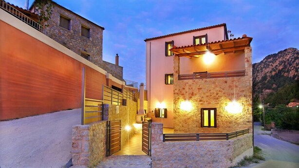 Un edificio de piedra de dos pisos con un balcón, una puerta de madera y una escalera de piedra que conduce a la entrada.