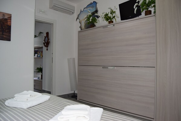 Una habitación de hotel con cama, armario, espejo y puerta que da a un baño.