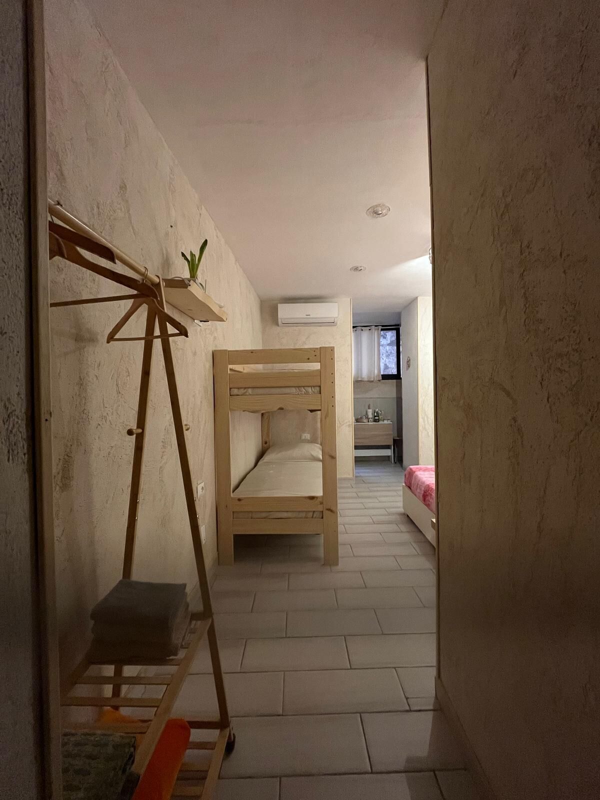 A narrow hallway with a bunk bed and a small table with a plant.