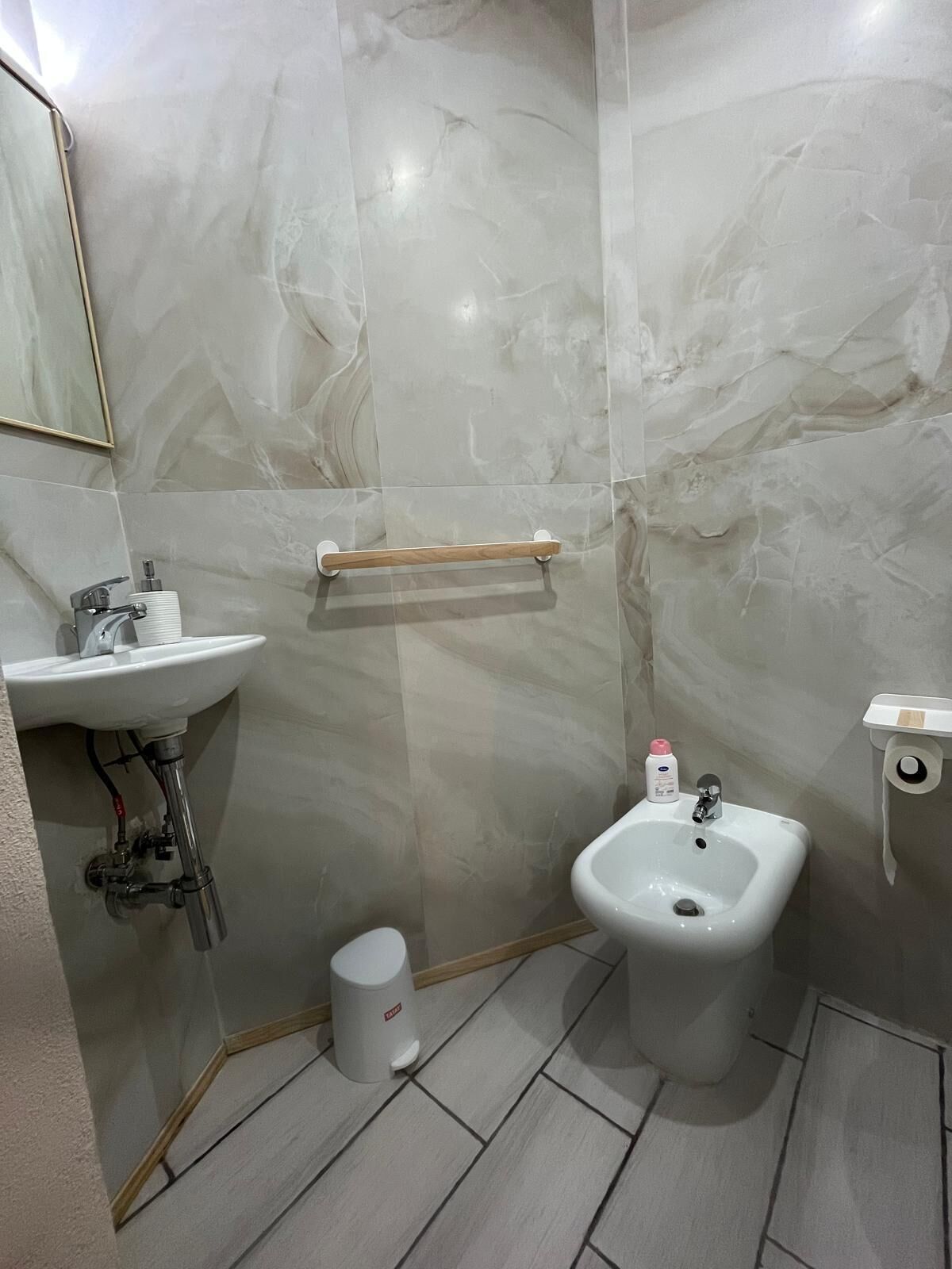 Un baño con lavamanos, bidé y secador de manos.