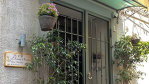 A building entrance with a metal gate, potted plants, and a signboard.