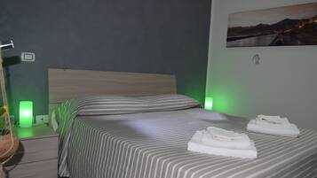Una habitación de hotel con cama, lámparas de noche, una mesita de noche y un cuadro en la pared.