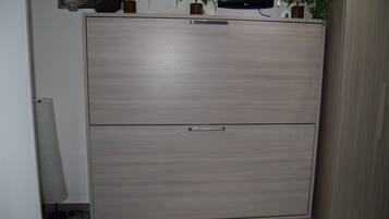 Ein Zimmer mit großem Kleiderschrank, einem wandmontierten Flachbildfernseher und zwei Blumentöpfen.