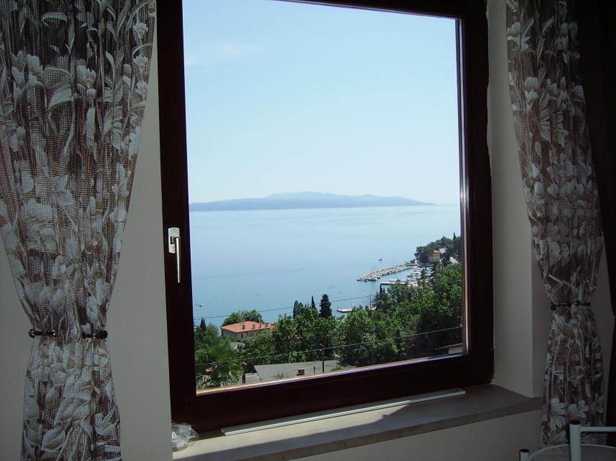 A room with a large window overlooking a coastal view.