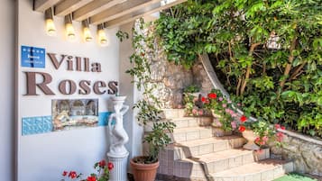 Villa Roses har en trappa av sten, krukväxter och en skylt.