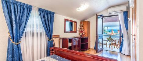 A bedroom with a bed, a dresser, a mirror, and a balcony with a view.